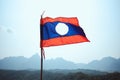 Closeup of the flag of Laos under the sunlight surrounded by mountains in Nam Xay in Vang Vieng