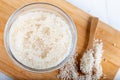 Closeup flat top lay view down of soaked rice, grain, cloudy liquid water in glass bowl on wooden background Royalty Free Stock Photo