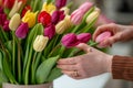 closeup of florists hands arranging tulips in a vase