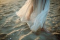 closeup of flowy dress hem as woman strolls on beach sand