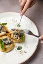 Closeup of the fork and knife in the hands of a person tasting the pancakes with topping