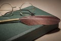 Closeup of fountain feather pen with vintage glasses on old green book. Selective focus Royalty Free Stock Photo