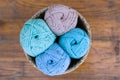 Closeup of four cotton balls in blue, mint, turosque and beige colors, assorted in small basket