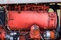 Closeup of four cylinder diesel tractor engine with visible belt rusty tracks hydraulic parts and wiring red paint in