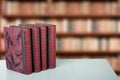 Closeup of four old books on bright table with a blurred bookshelf in library. Education concep Royalty Free Stock Photo