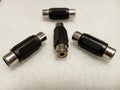 Closeup of four RCA adapters for audio cables audio cables on a white surface