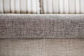 Closeup of a fragment of a beige textile sofa in the room. Texture of expensive fabric on furniture