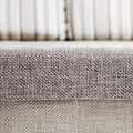 Closeup of a fragment of a beige textile sofa in the room. Texture of expensive fabric on furniture