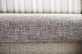 Closeup of a fragment of a beige textile sofa in the room. Texture of expensive fabric on furniture