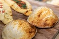 Closeup of fresh-baked Bazlama flatbread on background of appetizing stuffed pides