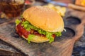 Closeup of fresh burger with French fries on wooden table with bowls of tomato sauce. lifestyle food Royalty Free Stock Photo