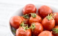 Closeup of fresh cherry tomatoes in white ceramic bowl on rustic Royalty Free Stock Photo