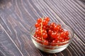 Closeup of the fresh and delicious redcurrants in a glass bowl on a wooden surface