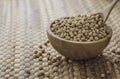 Closeup of fresh dry soybean seed in wooden bowl with spoon on Water hyacinth placemats