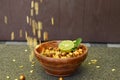 Closeup the fried yellow gram split lentils with black gram and sliced lemon ,mint in the red wooden bowl over out of focus brown Royalty Free Stock Photo