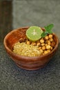 Closeup the fried yellow gram split lentils with black gram and sliced lemon ,mint in the red wooden bowl over out of focus brown Royalty Free Stock Photo