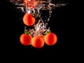 Closeup of fresh and health cherry tomatoes falling into clear water with big splash on black background. Group of fresh tomatoes Royalty Free Stock Photo