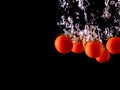 Closeup of fresh and health cherry tomatoes falling into clear water with big splash on black background. Group of fresh tomatoes Royalty Free Stock Photo