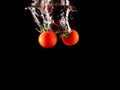 Closeup of fresh and health cherry tomatoes falling into clear water with big splash on black background. Group of fresh tomatoes Royalty Free Stock Photo