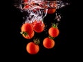 Closeup of fresh and health cherry tomatoes falling into clear water with big splash on black background. Group of fresh tomatoes Royalty Free Stock Photo