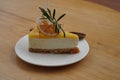 Closeup fresh honeyslice, dry orange slice, green leaf on yuzu cheese pie on white ceramic plate on wooden table background, food