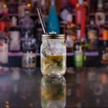 Closeup of fresh iced mojito with a straw in a jar on the bar with a blurry background