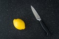 Closeup of fresh lemon on a black cutting board, paring knife, health and nutrition
