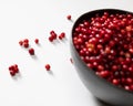 Closeup of fresh lingonberries in a bowl against a white background