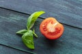 A closeup of a fresh organic heirloom tomato with vibrant green basil leaves, on a dark wooden background Royalty Free Stock Photo