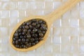 Closeup of fresh papaya seeds in wooden spoon on yellow tile background