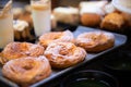 Closeup of fresh pastry with milk glases on morning cafe table top. Baked rings with sugar powder on black blur background