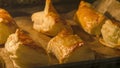 Puff pastry rolls with cheese. Fresh salty-sweet baking in oven. Several kinds of crispy pies lie in rows on a baking sheet on the