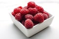 Closeup of fresh and ripe raspberries in the white bowl, white table Royalty Free Stock Photo