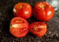 Closeup of fresh ripe tomatoes with water droplets on a black granite kitchen counter surface Royalty Free Stock Photo