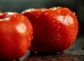 Closeup of fresh ripe tomatoes with water droplets on a black granite kitchen counter surface Royalty Free Stock Photo