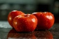 Closeup of fresh ripe tomatoes with water droplets on a black granite kitchen counter surface Royalty Free Stock Photo