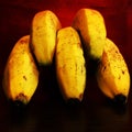 Closeup of yellow bananas bunch like fingers on red bloody background