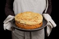 Closeup freshly baked homemade cherry pie with crumbs on top in the hands of the housewife.