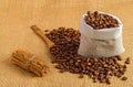 Closeup of freshly roasted coffee beans on a wooden table with a sack, spoons and cinnamon rolls Royalty Free Stock Photo