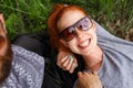 Closeup of a happiness girlfriend, seated down on a green grass, seated down with turned heads, in sunglasses.