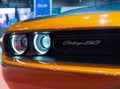 Closeup of the front and the headlights of an orange Dodge Challenger