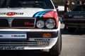 Closeup of the front of a Lancia Delta HF covered in stickers parked on the street