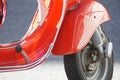 Closeup of the front part of red shiny Vespa scooter