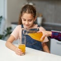 Closeup portrait of a hand pours cute little girl orange juice for breakfast Royalty Free Stock Photo