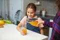 Closeup front portrait of a hand pours cute little girl orange juice. Royalty Free Stock Photo