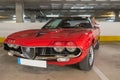 Closeup of the front view of a red vintage Coupe Alfa Romeo Montreal Coupe car in a garage