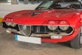 Closeup of the front view of a red vintage Coupe Alfa Romeo Montreal Coupe car in a garage