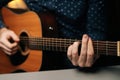 Closeup front view of unrecognizable guitarist male playing acoustic guitar sitting at desk in dark living room Royalty Free Stock Photo