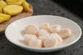 Closeup of frozen scallops in white bowl on walnut table for defrosting Royalty Free Stock Photo