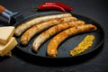 Closeup frying pan with fried thin sausages, mustard, chili, and cheese